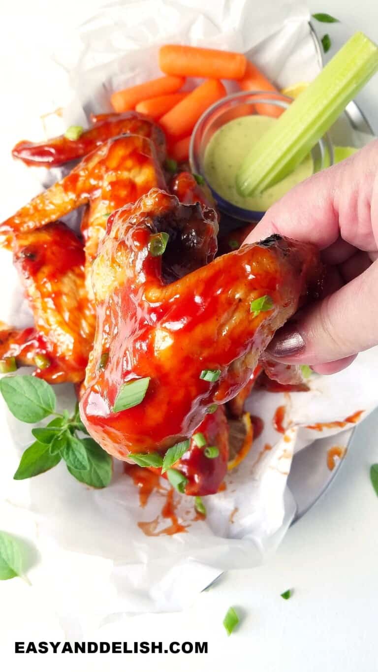 a hand holding a bbq chicken wing cooked in the air fryer