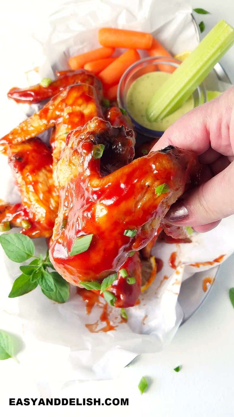 a hand holding a bbq chicken wing cooked in the air fryer