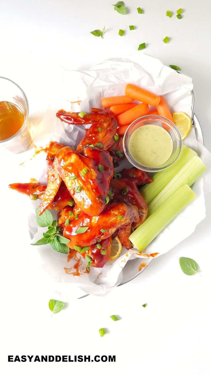 bbq chicken wings ina platetr with vegetables and a dressing