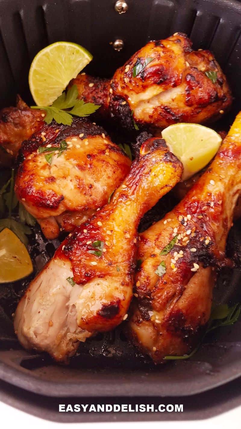 air fryer chicken drumsticks in air fryer tray with garnishes