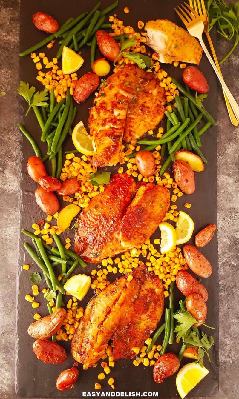 cutting board with fried fish and vegetables plus cutlery