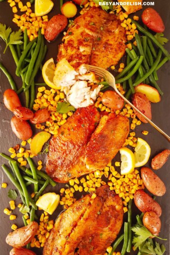 several air fryer tilapia fillets over a board with vegetables