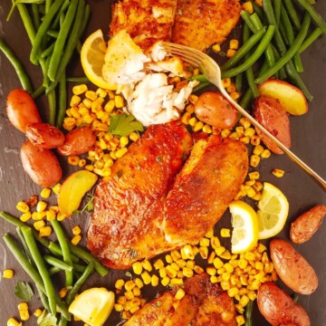 several air fryer tilapia fillets over a board with vegetables