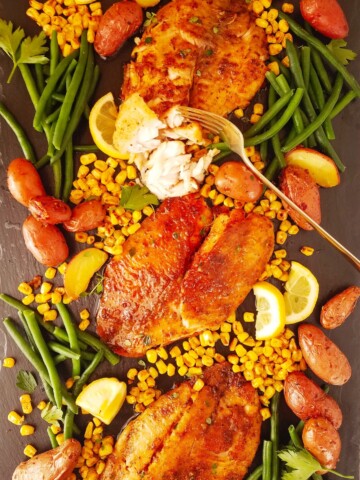 several air fryer tilapia fillets over a board with vegetables