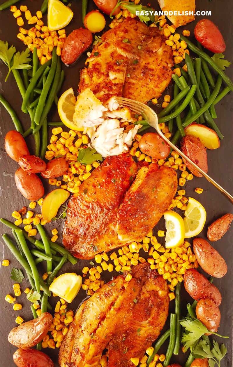 several air fryer tilapia fillets over a board with vegetables