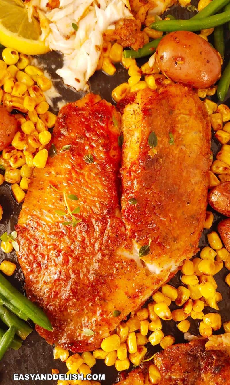 close up de um filé de tilapia na air fryer por cima de uma tábua com verduras