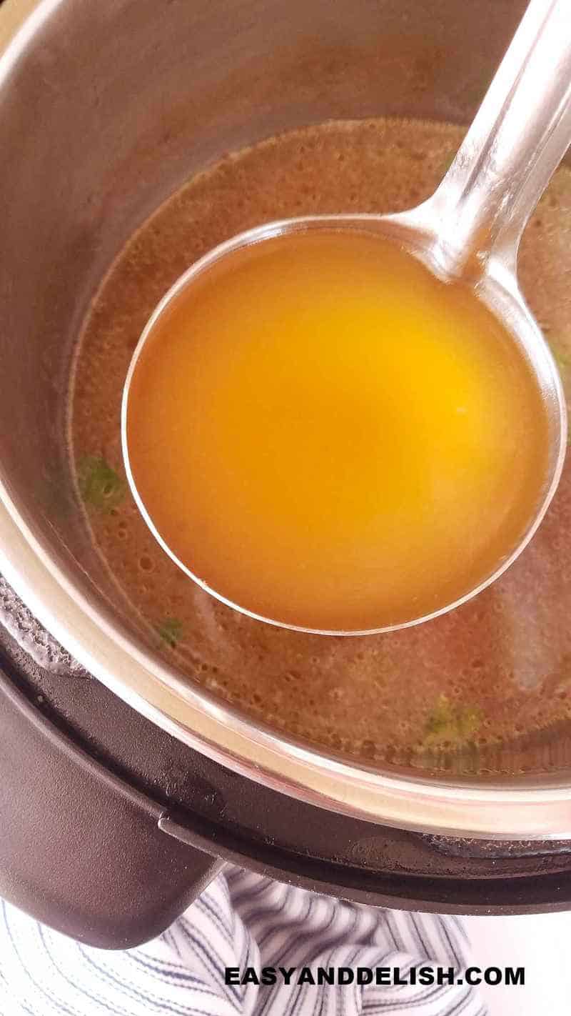 caldo de frango em uma concha dentro da panela de pressão