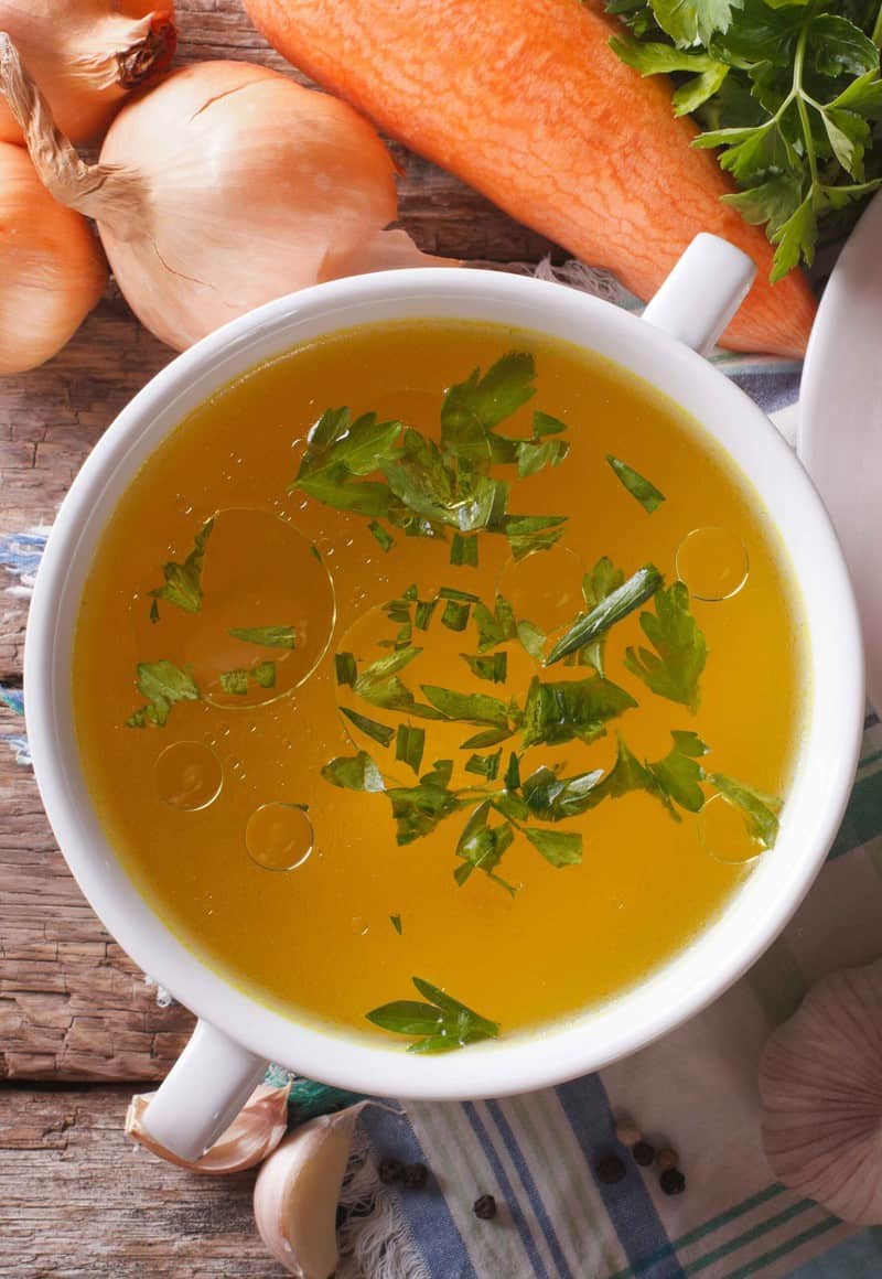 uma tigela de caldo de galinha com verduras ao lado