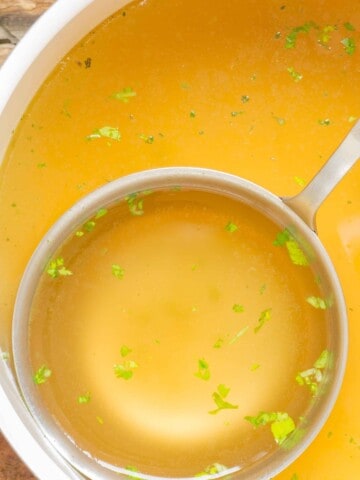 close up of a ladle full of chicken bone broth