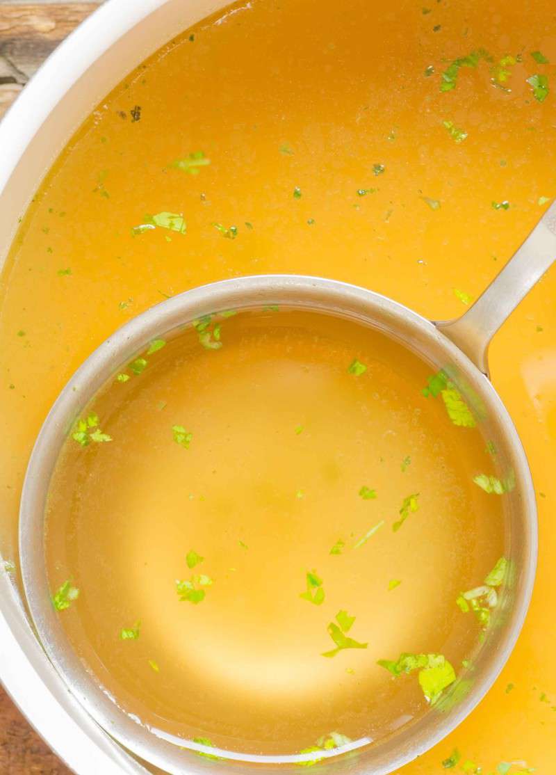 close up of a ladle full of chicken bone broth