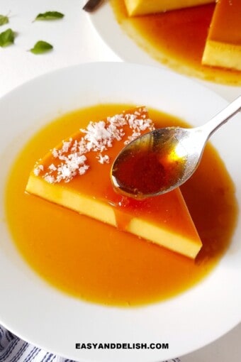 a spoon drizzling caramel over a slice of coconut flan