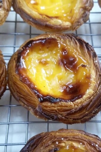 pastel de belém assado descansando em cima de uma gradinha