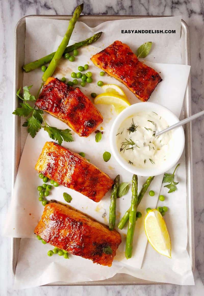 air fryer salmon filets in a baking sheet with veggies and sauce