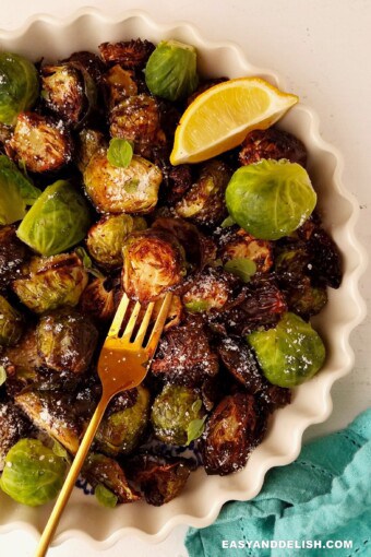 half bowl of air fryer Brussels sprouts with a wedge of lemon