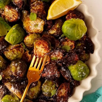 half bowl of air fryer Brussels sprouts with a wedge of lemon
