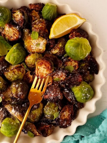 half bowl of air fryer Brussels sprouts with a wedge of lemon