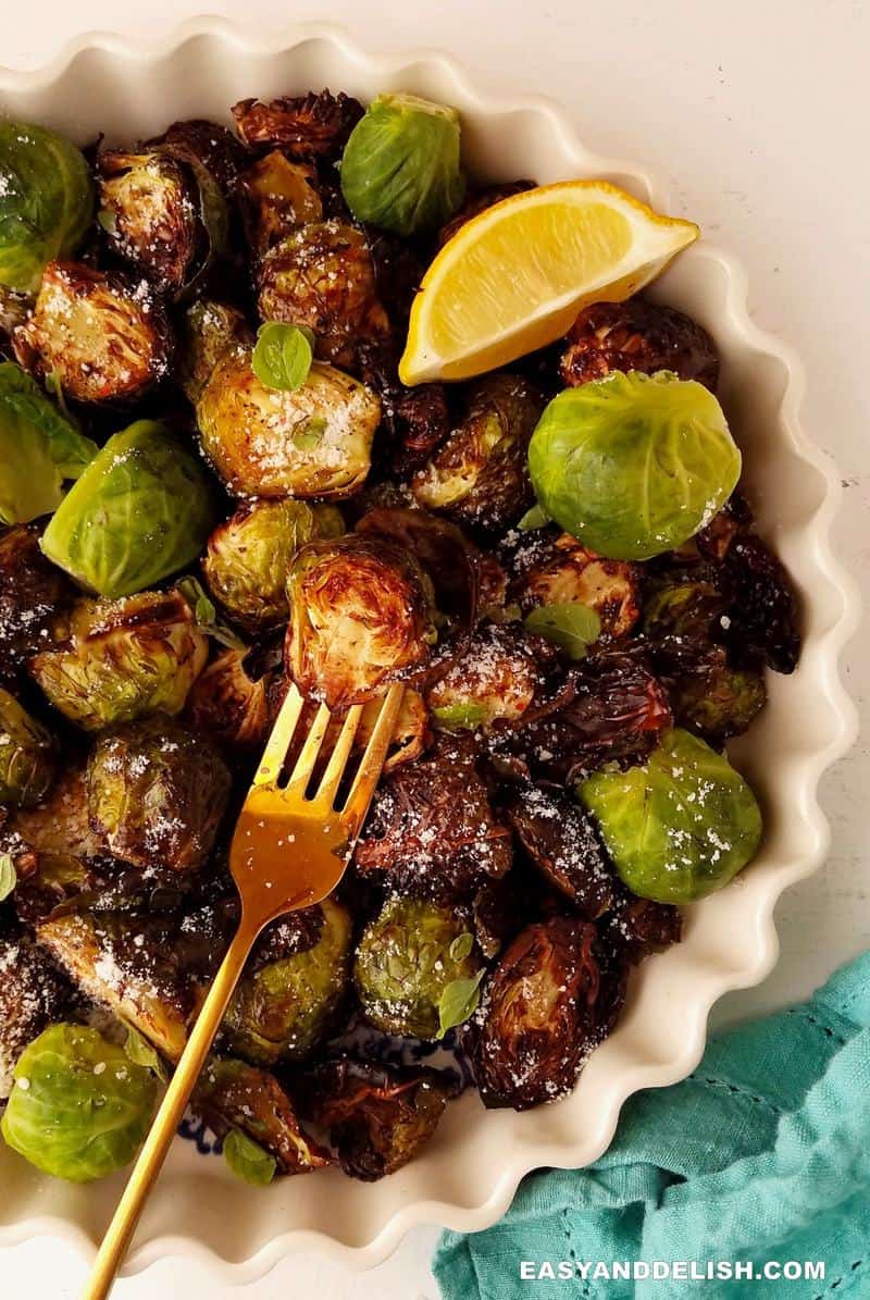 half bowl of air fryer Brussels sprouts with a wedge of lemon