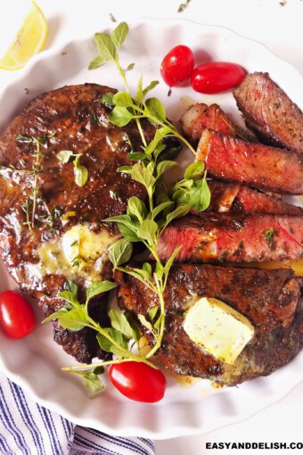 whole and sliced air fryer steak in a plate with garnishes on top