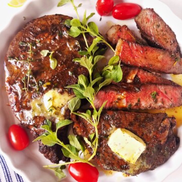 whole and sliced air fryer steak in a plate with garnishes on top