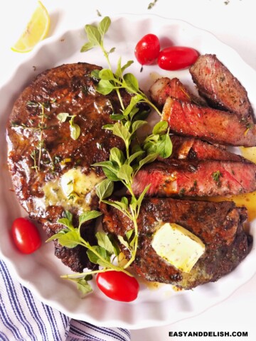 whole and sliced air fryer steak in a plate with garnishes on top