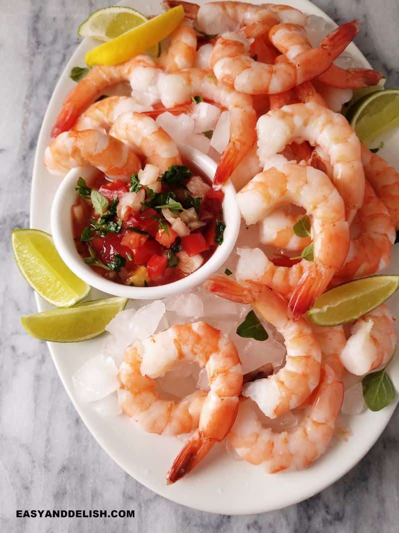 close up of a platter of Mexican shrimp cocktail with salsa in a bowl