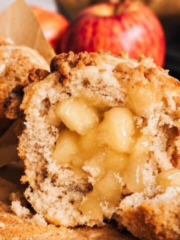 Apple muffin cut open to show the soft apple pie filling in the center.