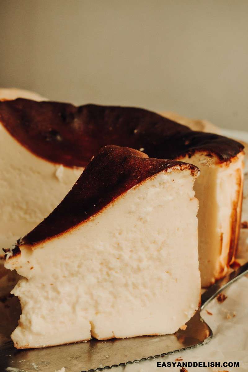 a slice of basque cheesecake with the rest of the dessert on the background