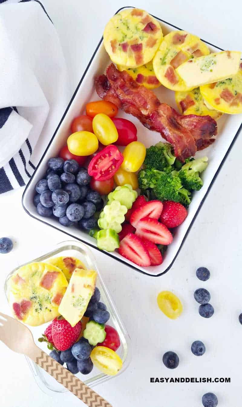 2 meal prep containers with breakfast muffins plus bacon, fruits and veggies