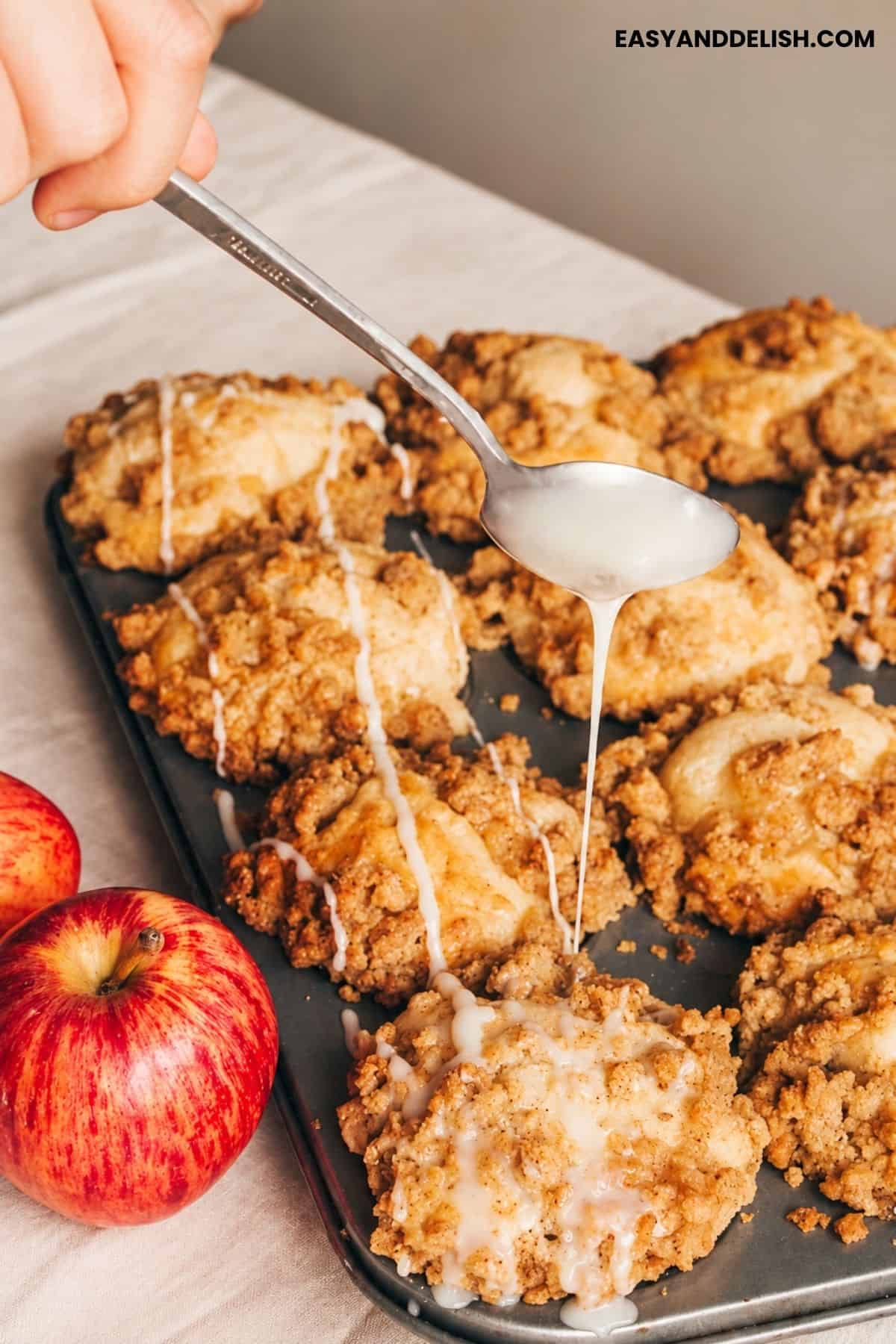 Vanilla glaze drizzled over an apple muffin with crumble topping.
