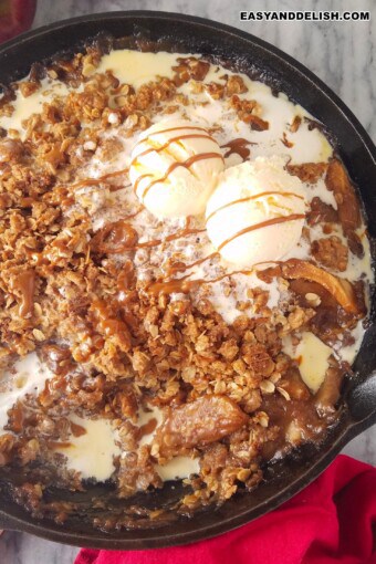 a skillet with gluten-free apple crisp topped with ice cream and dulce de leche sauce