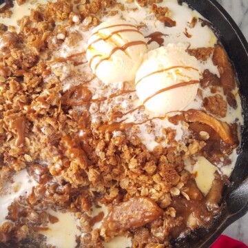 a skillet with gluten-free apple crisp topped with ice cream and dulce de leche sauce