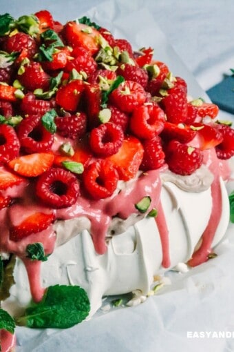 a pavlova topped with chocolate cream, berry curd, and berries