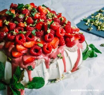 a pavlova topped with chocolate cream, berry curd, and berries