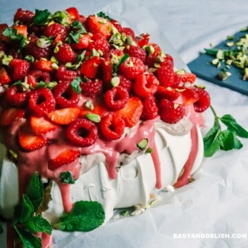 a pavlova topped with chocolate cream, berry curd, and berries