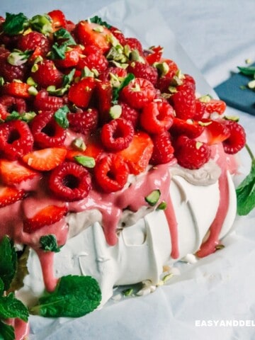 a pavlova topped with chocolate cream, berry curd, and berries