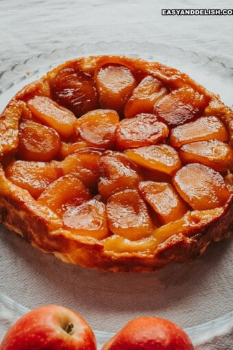 tarte tatin inteira com umas maçãs perto