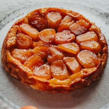 tarte tatin inteira com umas maçãs perto