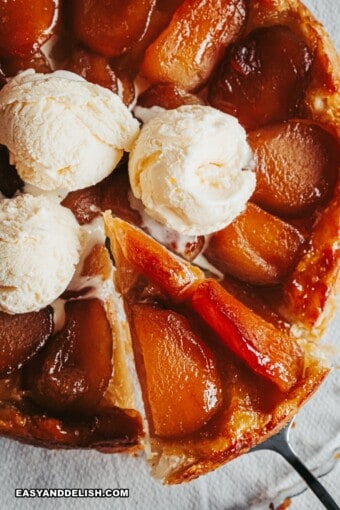 a slice of tarte tatin held up with the rest of the dessert under with ice cream