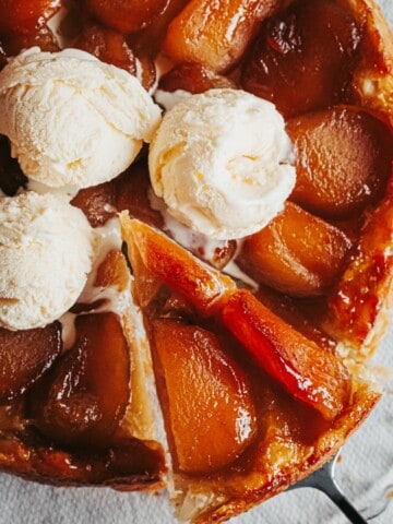 a slice of tarte tatin held up with the rest of the dessert under with ice cream