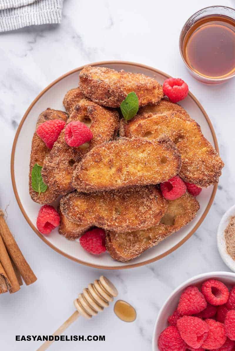 rabanadas with garnishes on the side such as honey and berries