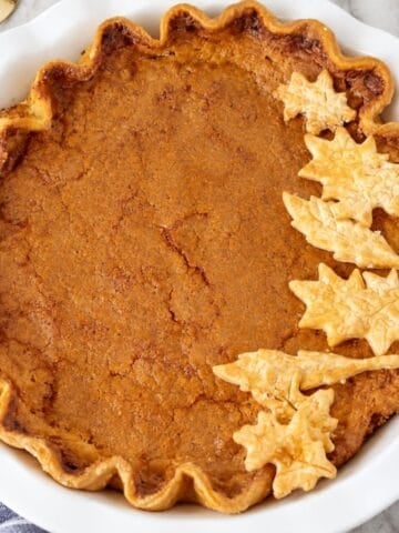 Overhead view of a golden brown buttermilk pie decorated with pastry leaves.