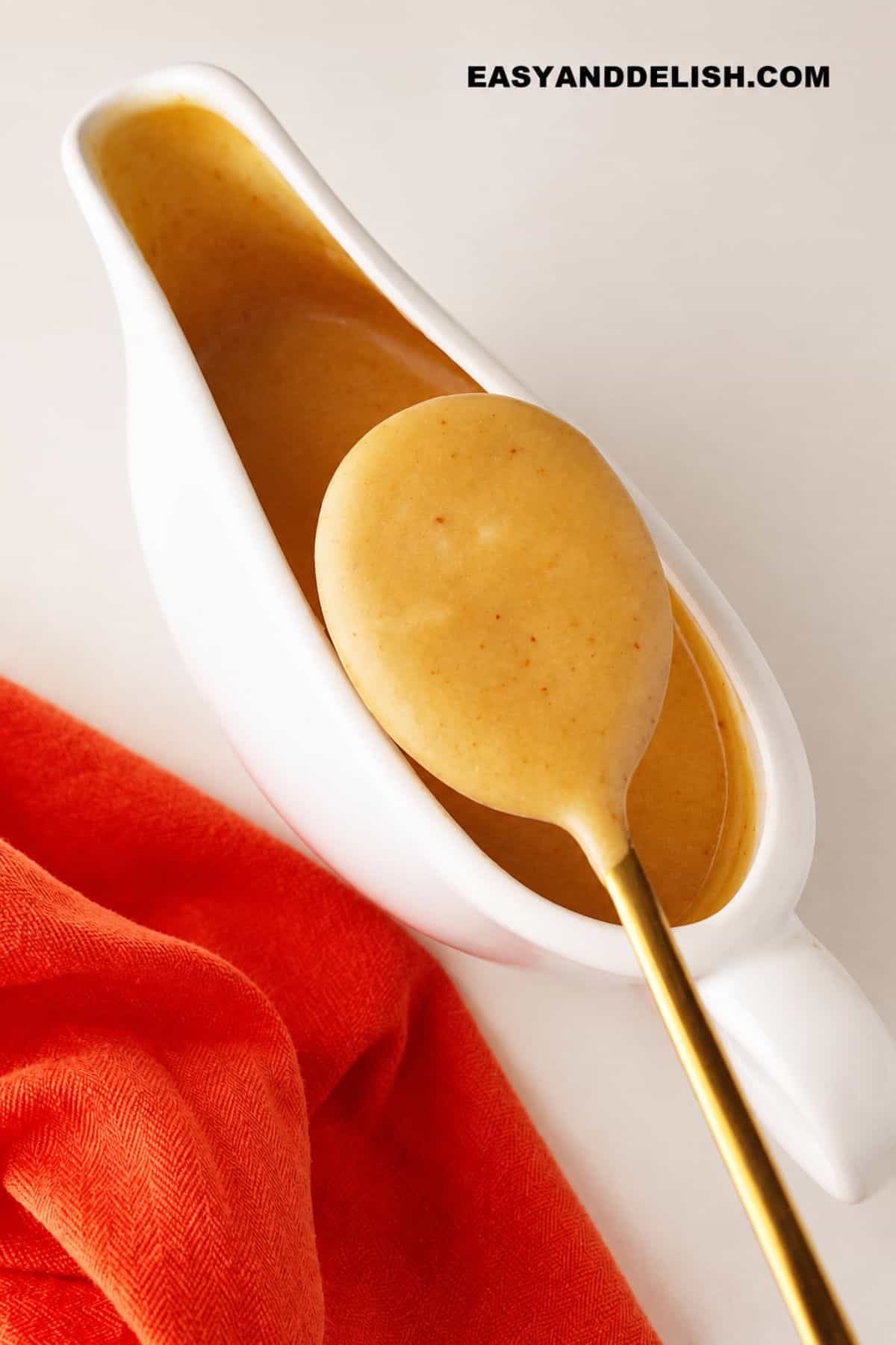 Smooth homemade turkey gravy in a white gravy boat with a spoon.
