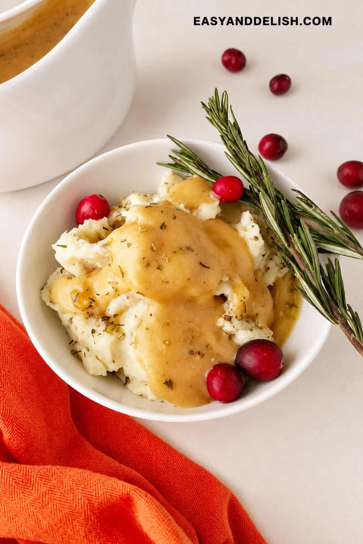 Savory gravy spooned over mashed potatoes with rosemary and cranberries.