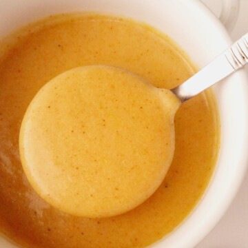 close up of a bowl of gravy with a laddle being lifted
