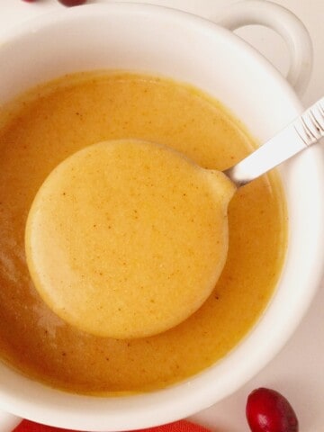 close up of a bowl of gravy with a laddle being lifted