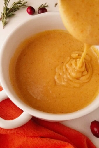 a laddle pouring gluten-free turkey gravy inside of a bowl