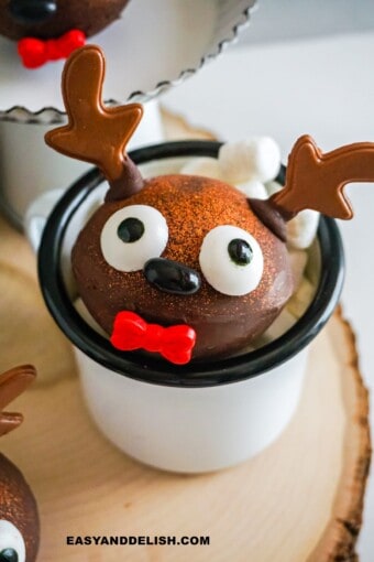 a hot chocolate bomb decorated for Christmas inside of a mug