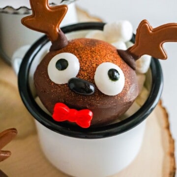 a hot chocolate bomb decorated for Christmas inside of a mug