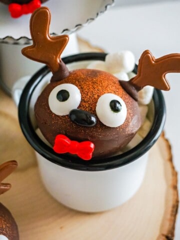 a hot chocolate bomb decorated for Christmas inside of a mug