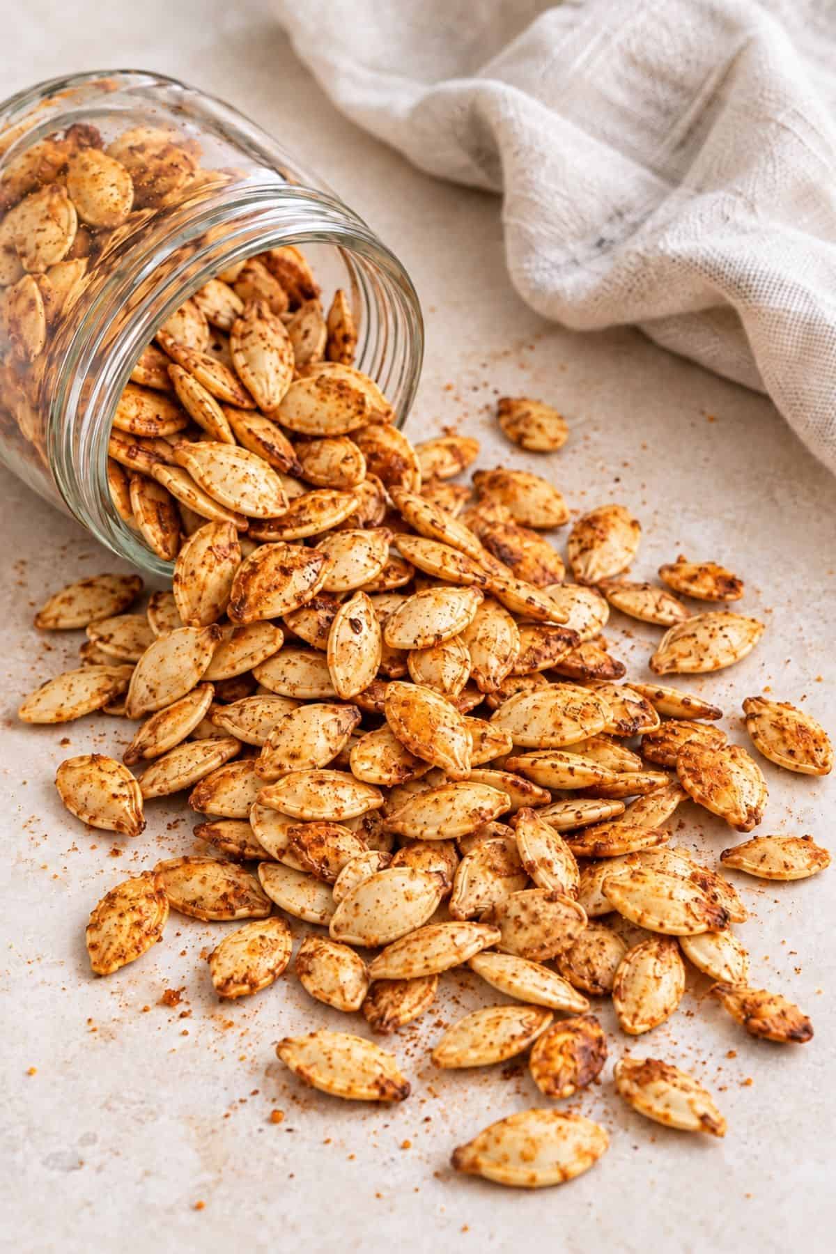 Taco-seasoned roasted pumpkin seeds with golden edges on a stone surface.